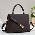 Detail view of dark brown textured handbag with gold twist lock and elegant top handle - Coffee