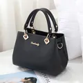 Klassische schwarze Lederhandtasche mit goldenen Griffen und Danbaoly-Logo auf Sofa - 27x19x14cm / Schwarz