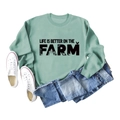 Flat lay of green sweatshirt with Life Is Better On The Farm text and tractor graphics - Light Green Sweatshirt (Black Text Pattern)
