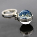 Vista macro di un portachiavi a sfera di vetro con paesaggio natalizio e neve - Capanna Innevata e Chiesa (JY008216-12)