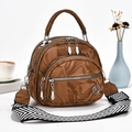 Detail view of glossy brown marble textured handbag with metal K logo and woven strap - Brown