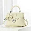 Detail of creamy white faux leather tote with silver ring lock and pearl bow charm - Off White