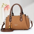 Close-up of brown leather tote bag with wooden bead charm and minimalist lettering - Earthy Yellow