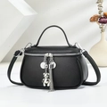 Elegant black pebble grain handbag with bear charm and tassel on minimalist display - Black