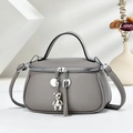 Grey pebbled leather handbag with bear pendant and detachable shoulder strap in studio light - Gray