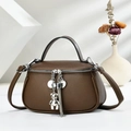Elegant brown pebble leather handbag with silver bear charm and stylish tassel detail - Coffee