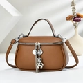 Detailed macro view of brown litchi pattern leather bag with silver bear charm tassel - Earthy Yellow