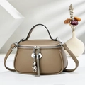 Detail of tan pebble leather handbag featuring a silver bear charm and chain tassel - Khaki