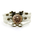 Dettaglio del bracciale steampunk multistrato in pelle con ingranaggi in bronzo e teschio - Bianco