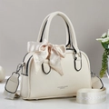 Detail of cream leather handbag with litchi texture and decorative floral bow charm - Off White
