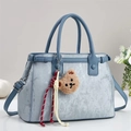 Sac à main bleu clair texturé avec pendentif ours dans un décor de maison élégant - Bleu