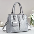 Chic silver metallic tote bag with tassels and shoulder strap on a minimalist desk - Gray