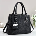 Schwarze Handtasche mit Textur, Schnallen und Anhänger auf elegantem weißem Hintergrund - Schwarz