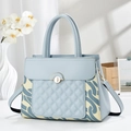 Détail macro d'un sac à main matelassé bleu avec serrure dorée et motifs de fleurs - Bleu