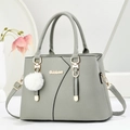 Gray-green pebbled leather tote bag with top handles and a plush charm on a minimal background - Gray