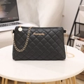 Quilted black crossbody bag with gold chain strap on white marble table for daily use - Black