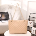 Beige quilted tote bag with diamond stitching and gold chain straps in home setting - Khaki