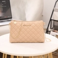Beige quilted crossbody phone bag with gold chain strap and metal logo on a table - Apricot