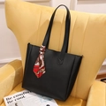 Minimalist black faux leather tote bag with elegant silk scarf on yellow sofa - Black