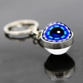 Macro shot of silver Evil Eye keychain with glass dome and reflection on dark surface - Classic Turkish Evil Eye Style (JY008522-5)