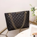 Sac fourre-tout matelassé noir élégant avec chaîne dorée et logo en métal sur table chic - Noir