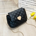 Close-up of black quilted saddle bag with golden heart-shaped lock and chain strap - Black
