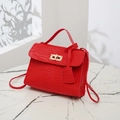 Elegant red crocodile pattern crossbody bag with a golden twist lock on marble stand - Red