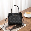 Top-down view of black handbag with vintage floral print on a cozy wooden table - Black