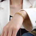 Chunky gold chain bracelet with geometric letter links and star detail on white suit - Gold T-Style / Letter Design (E090)