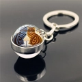 Macro shot of glass dome keychain featuring two cats illustration on black reflective base - Blue and Orange Cats Autumn(XSWX2233-9)