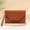Brown envelope clutch bag with V-flap design and gold logo on a natural woven mat - Brown