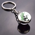 Close-up of a panda eating bamboo illustration in a round glass dome keychain pendant - Panda in Bamboo Forest (JY008711-10)