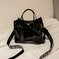 Borsa a secchiello in vernice nera lucida con tracolla a scritte bianche e fibbia dorata - Nero