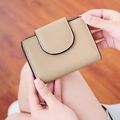 Primer plano de una elegante billetera de cuero PU beige sostenida por una modelo en interior - Caqui