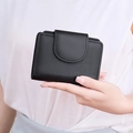 Close-up of black lychee grain leather wallet with snap closure and stitched details - Black