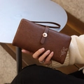 Macro view of vintage brown leather long wallet featuring leaf embossing and petal clasp - Coffee