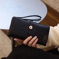 Detail of matte black long wallet featuring floral buckle and embossed leaf accents - Black