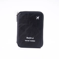Detail of black travel wallet showing pebble leather texture and silver airplane logo - Black