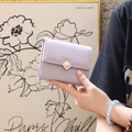 Vue détaillée du portefeuille lilas à trois volets avec un fermoir cœur décoratif - Violet