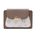 Detailed view of women's bi-fold wallet featuring pebble leather and metal leaf pendant - Coffee