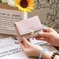 Detailansicht der hellrosa Damen-Geldbörse mit goldenem Herzverschluss in der Hand - Rosa
