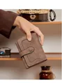 Nahaufnahme einer braunen Wildleder-Geldbörse mit weißen Nähten vor Retro-Hintergrund - Kaffeebraun