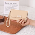 Detail of beige wristlet wallet featuring a bow-shaped gold buckle and delicate PU texture - Yellow