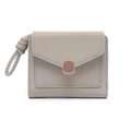 Detalle de cartera beige minimalista con solapa de sobre, hebilla y correa de muñeca - Verde