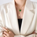 Collar dorado con colgante esmeralda y anillo ancho sobre modelo en traje blanco - Collar / Cristal Verde Dorado