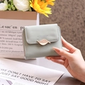 Detailed view of women's short wallet with metal leaf clasp and engraved brand logo - Green