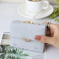 Detail of grey-blue quilted leather wallet with gold leaf clasp and floral prints - Gray