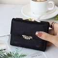 Close-up of black matte wallet with leaf embossing and golden buckle held by hand - Black