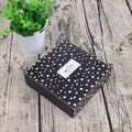 Schwarze Schachtel mit weißen Punkten und Merci-Aufkleber auf hellem Holzboden - Polka Dot Stil