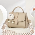 Beige pebble leather handbag with woven strap and plush charm on white stand - Khaki